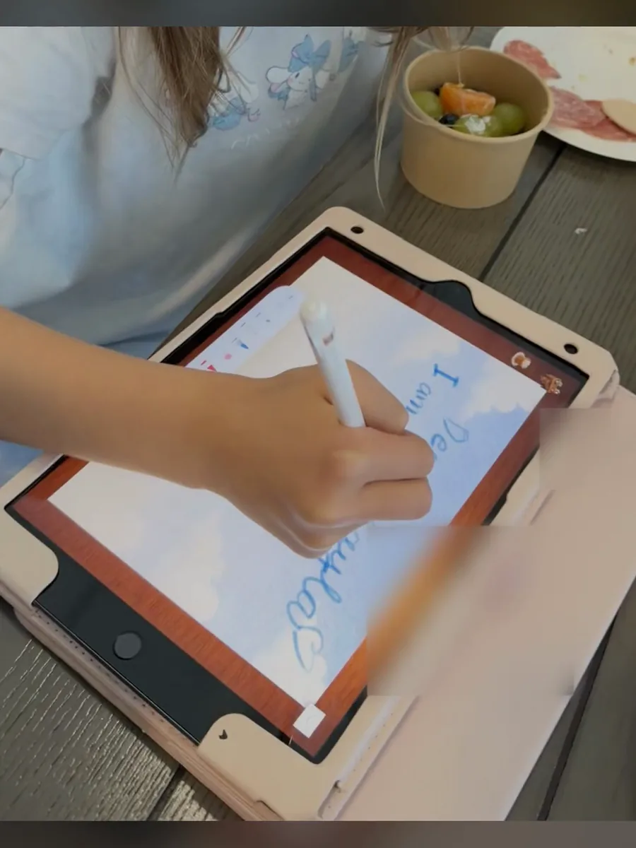 A hand writing a letter with an Apple Pencil on an iPad, from a reel of letters being made